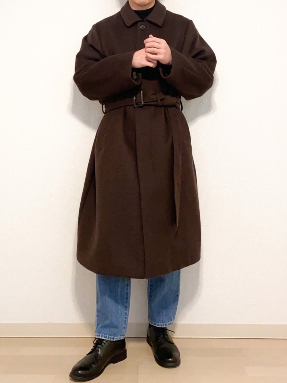 グレー系のステンカラーコート、ブラック系のニット/セーター、その他のデニムパンツを着用したメンズの冬コーディネートの1枚目の写真