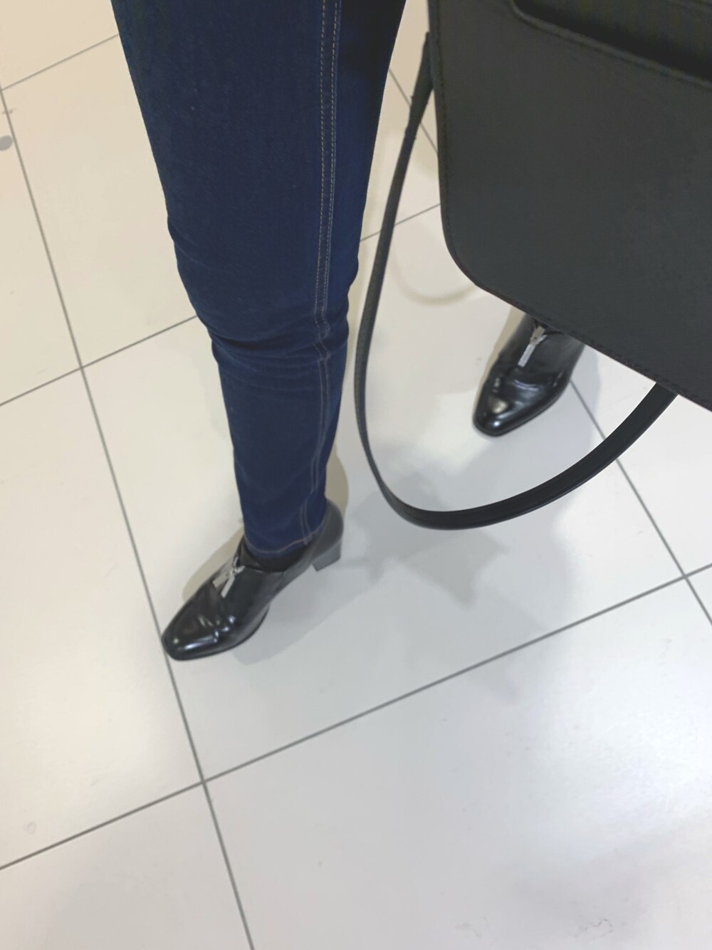 ブラック系のデニムパンツ、ブラック系のブーツ、ブラック系のショルダーバッグを着用したレディースの秋コーディネートの1枚目の写真