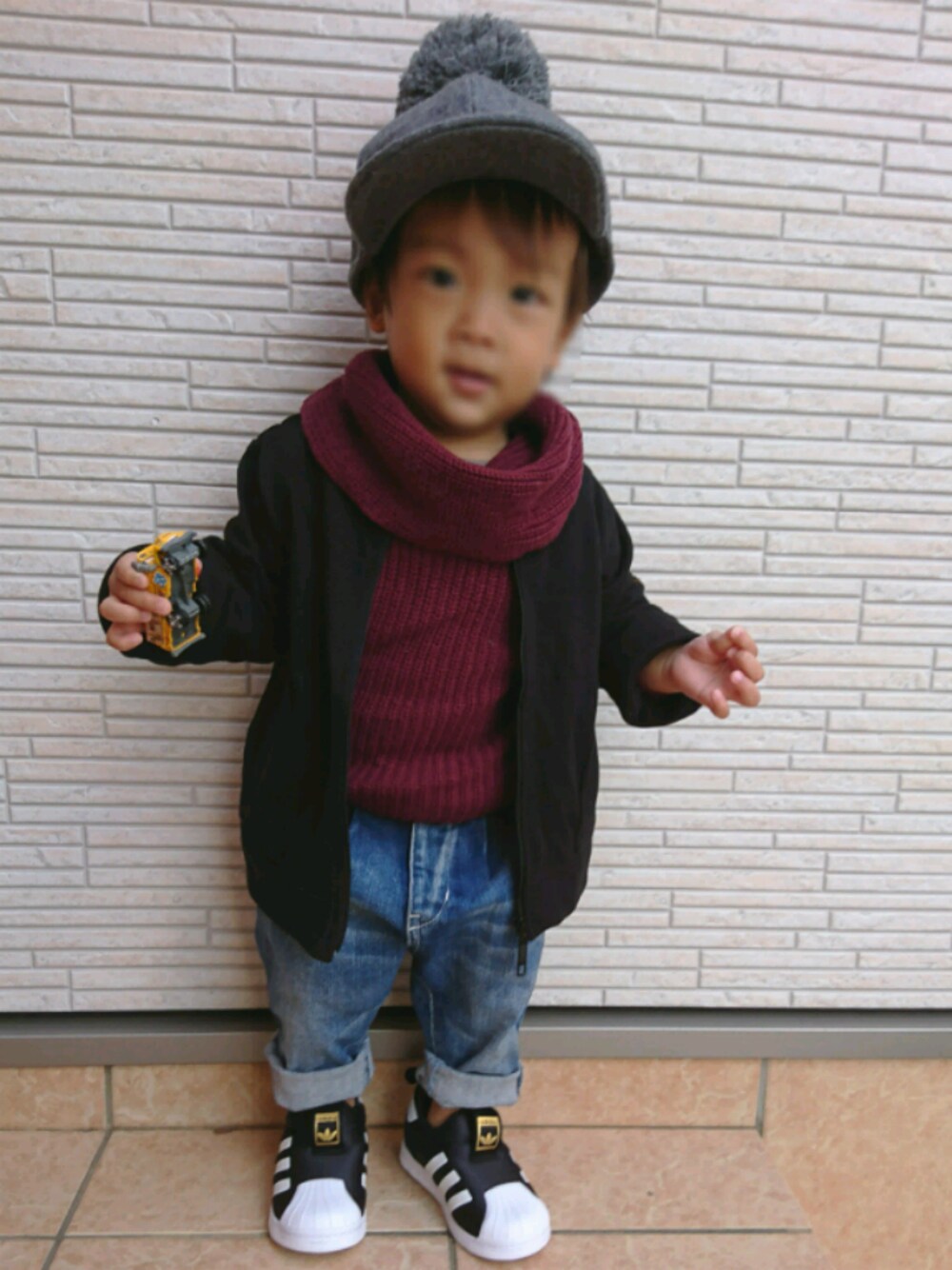 ブラック系のスリッポン、ブラック系のカーディガン/ボレロ、ブルー系のデニムパンツを着用したキッズの秋コーディネートの1枚目の写真