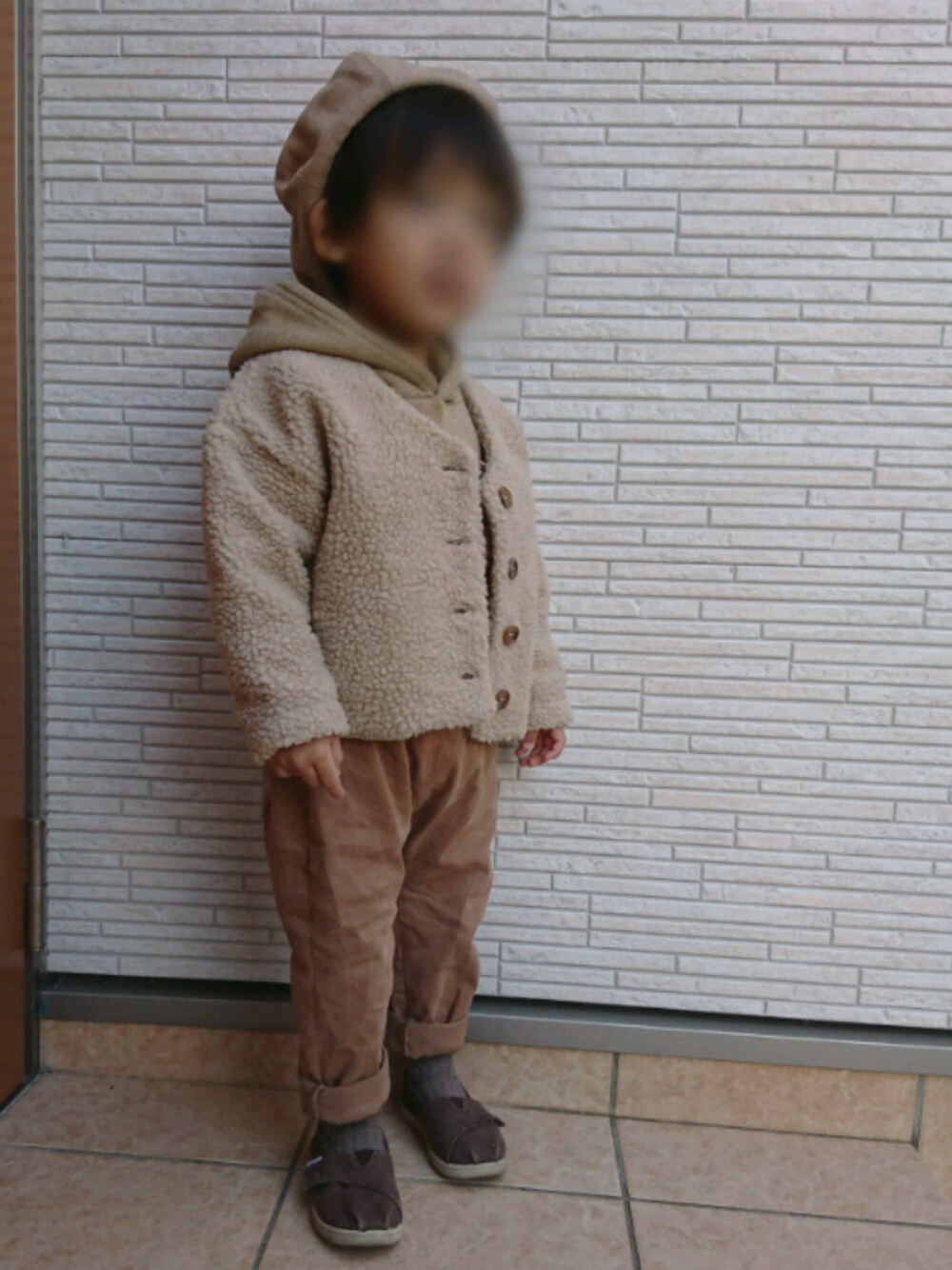 ベージュ系のパーカー、ベージュ系のカーディガン/ボレロ、ブラウン系のスニーカーを着用したキッズの冬コーディネートの1枚目の写真