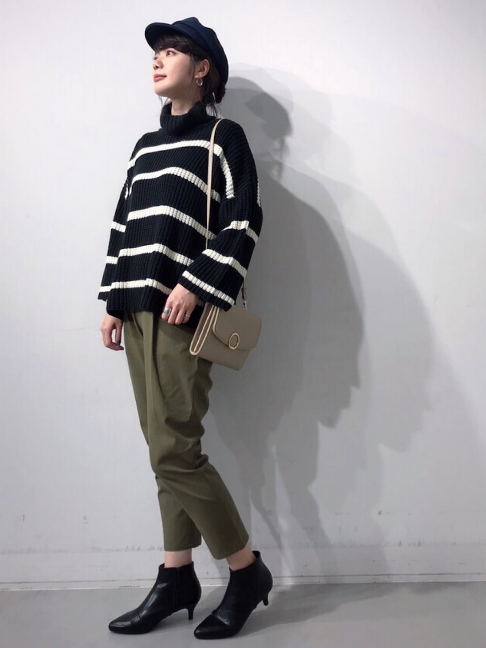 ブラック系のニット/セーター、グリーン系のその他パンツ、ベージュ系のショルダーバッグを着用したレディースの冬コーディネートの1枚目の写真