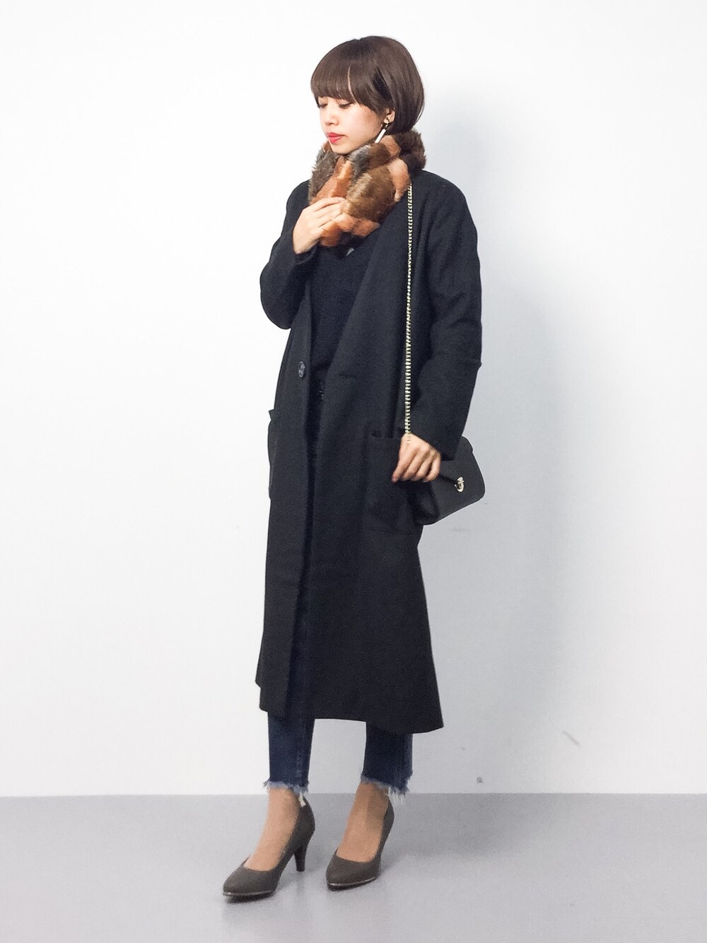 ブラック系のチェスターコート、ブルー系のデニムパンツ、グレー系のパンプスを着用したレディースの冬コーディネートの1枚目の写真