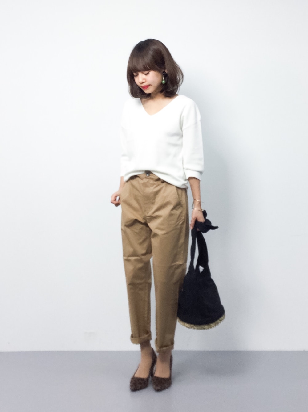 ホワイト系のニット/セーター、ベージュ系のチノパンツ、ブラック系のショルダーバッグを着用したレディースの春コーディネートの1枚目の写真