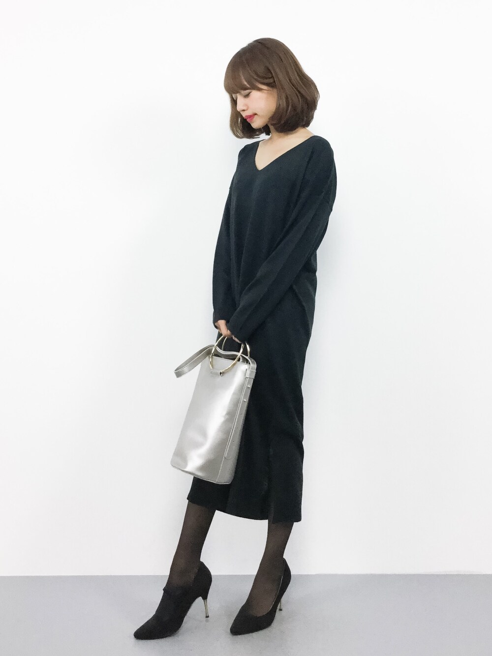 ブラック系のワンピース、シルバー系のハンドバッグを着用したレディースの秋コーディネートの1枚目の写真