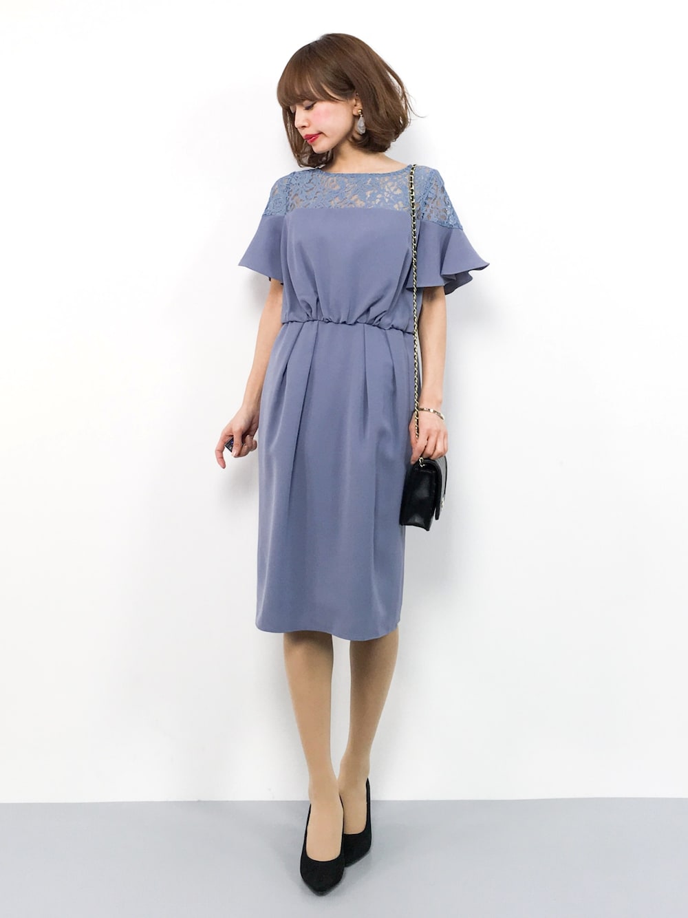 ブルー系のドレス、ブラック系のパンプス、ブラック系のショルダーバッグを着用したレディースの冬コーディネートの1枚目の写真