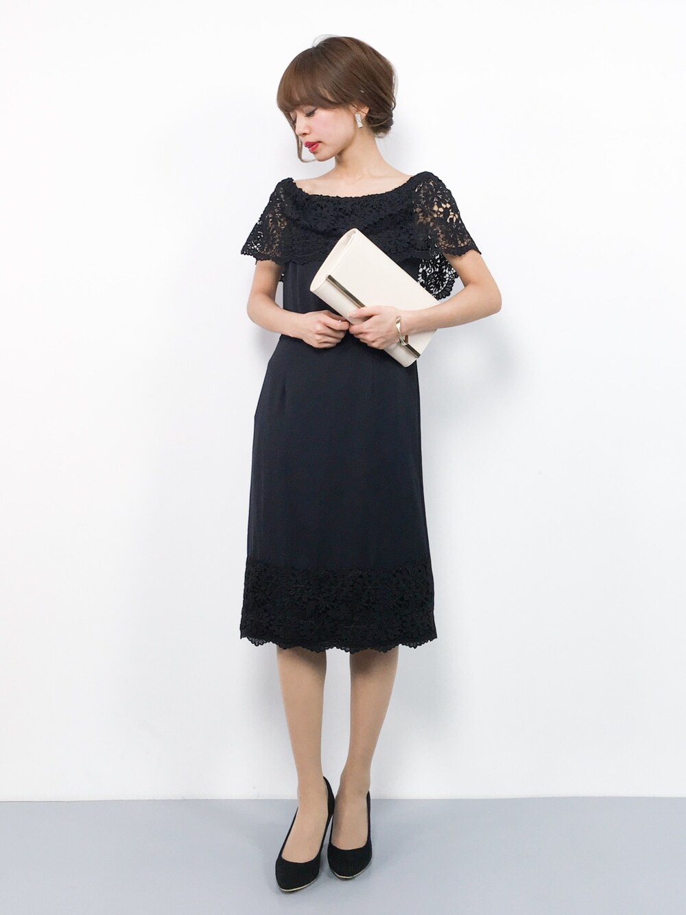 ブラック系のドレス、ブラック系のパンプス、ベージュ系のクラッチバッグを着用したレディースの冬コーディネートの1枚目の写真