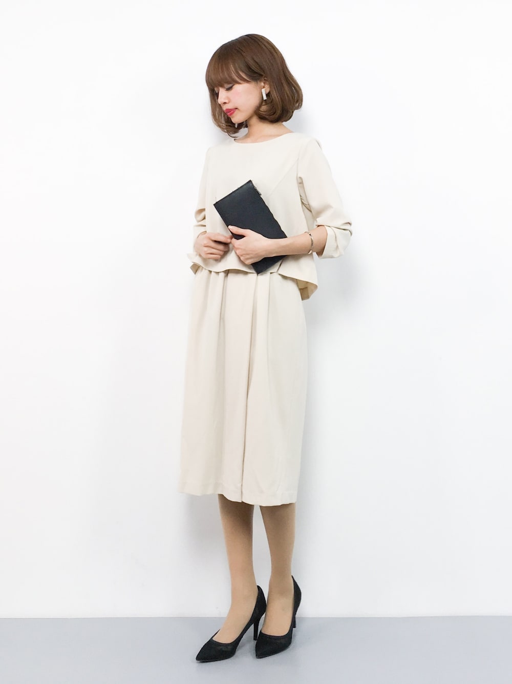 ベージュ系のワンピース、ブラック系のパンプスを着用したレディースの春コーディネートの1枚目の写真