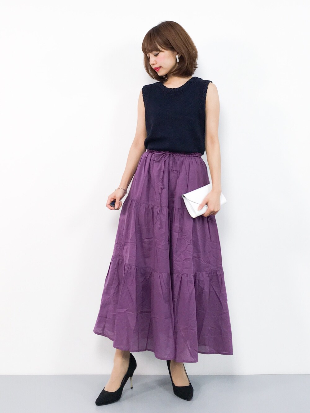 ブルー系のニット/セーター、パープル系のスカート、ホワイト系のボディバッグ/ウエストポーチを着用したレディースの夏コーディネートの1枚目の写真