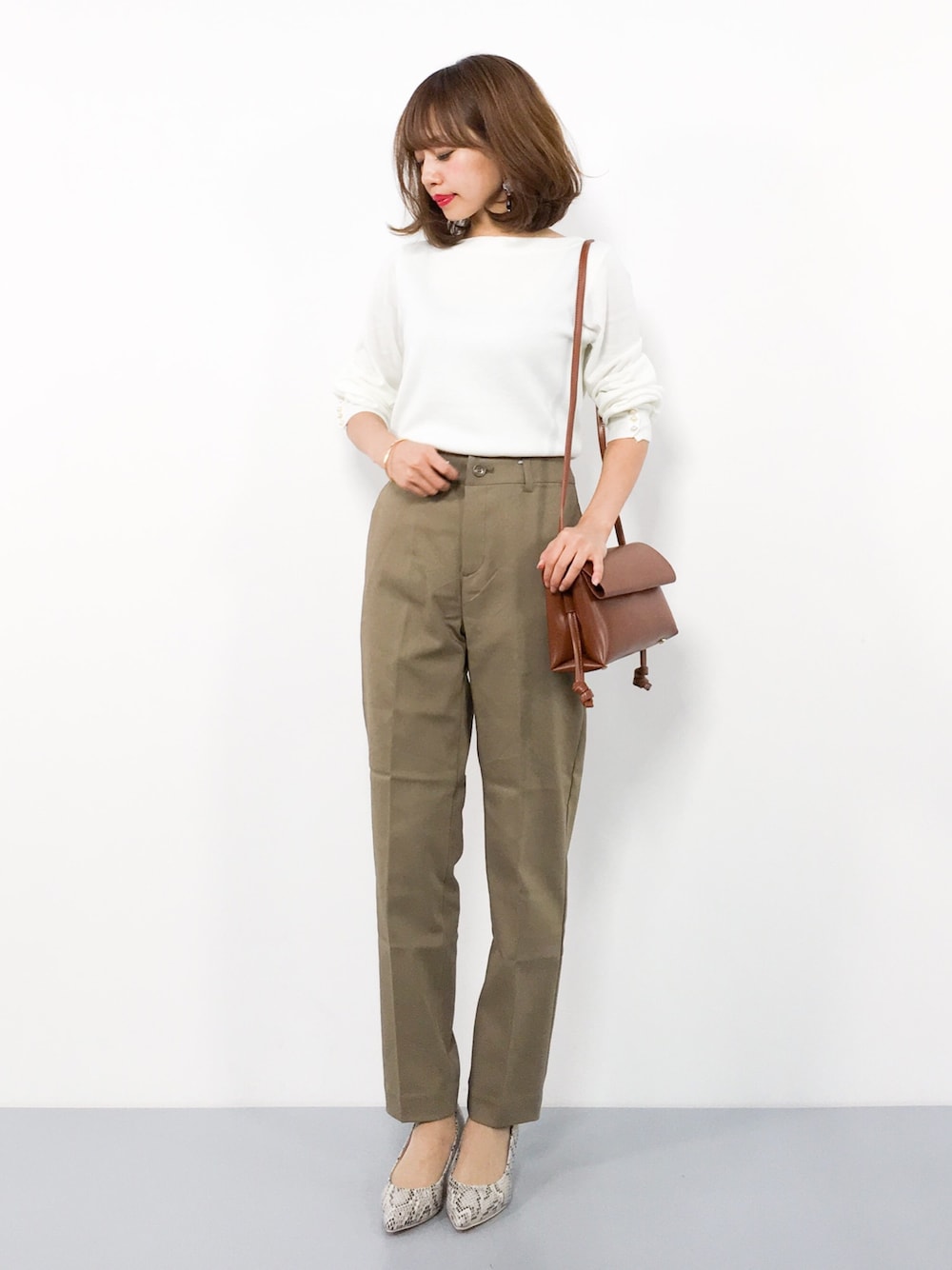 ホワイト系のニット/セーター、ブラウン系のその他パンツ、イエロー系のショルダーバッグを着用したレディースの秋コーディネートの1枚目の写真