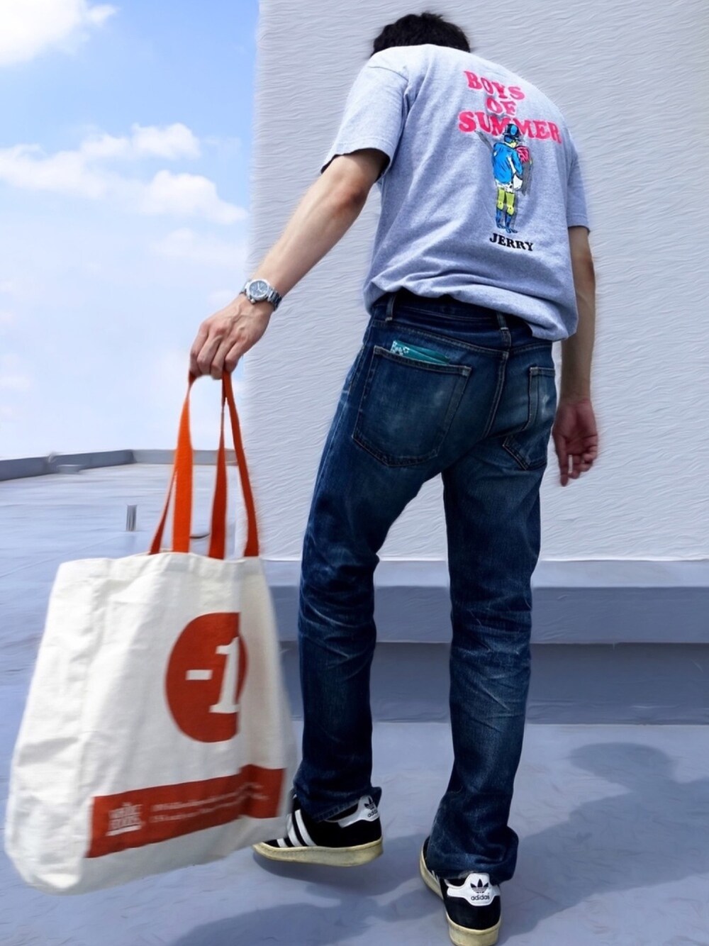 グレー系のTシャツ/カットソー、ブルー系のデニムパンツ、ブラック系のスニーカーを着用したメンズの夏コーディネートの1枚目の写真