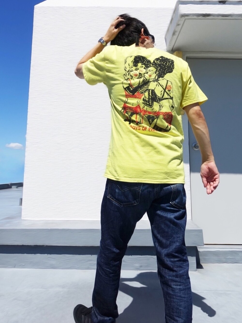 イエロー系のTシャツ/カットソー、ブラック系のスニーカー、ブルー系のデニムパンツを着用したメンズの秋コーディネートの1枚目の写真