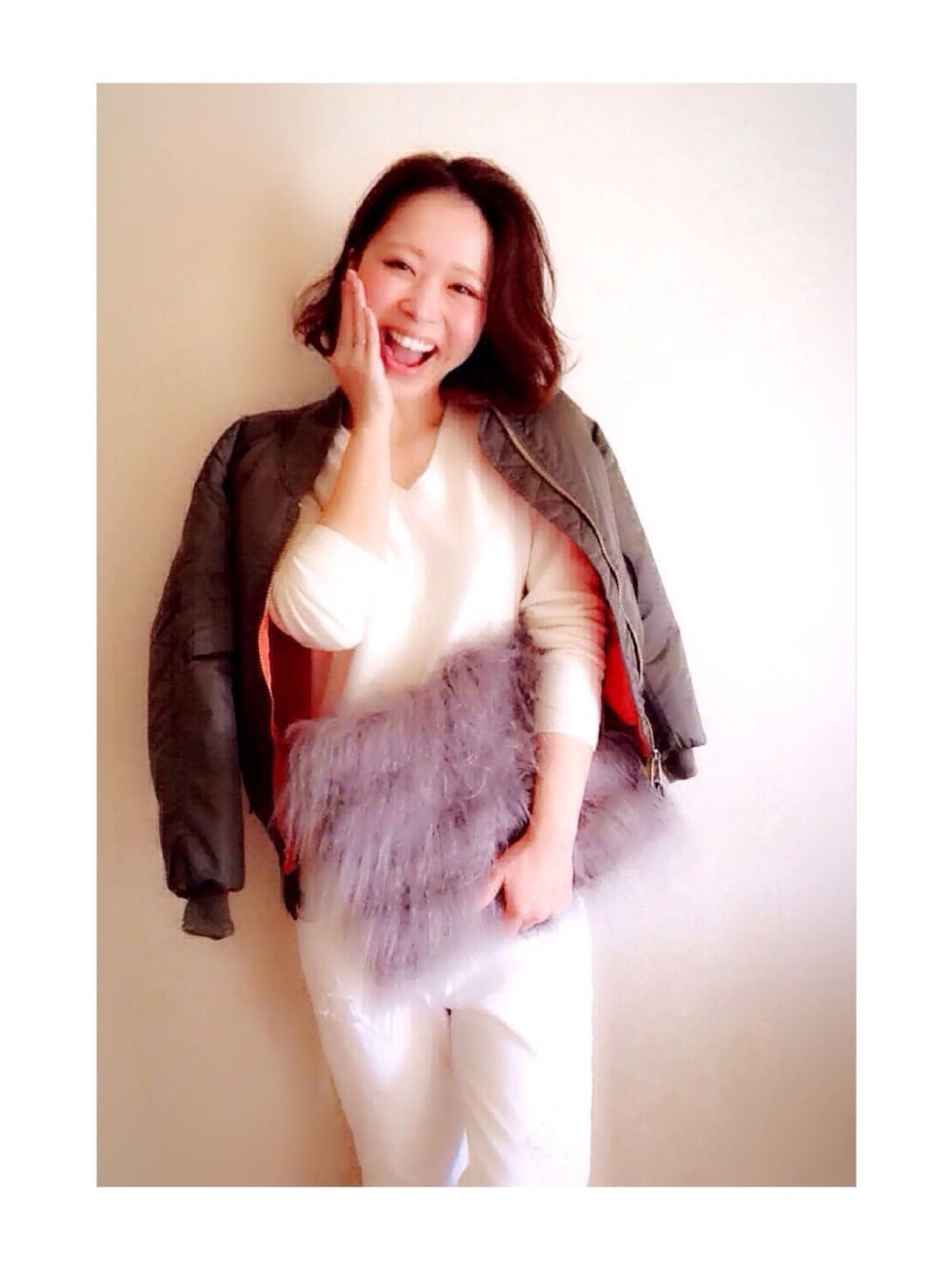 グリーン系のブルゾン、ホワイト系のニット/セーター、グレー系のクラッチバッグを着用したレディースの秋コーディネートの1枚目の写真