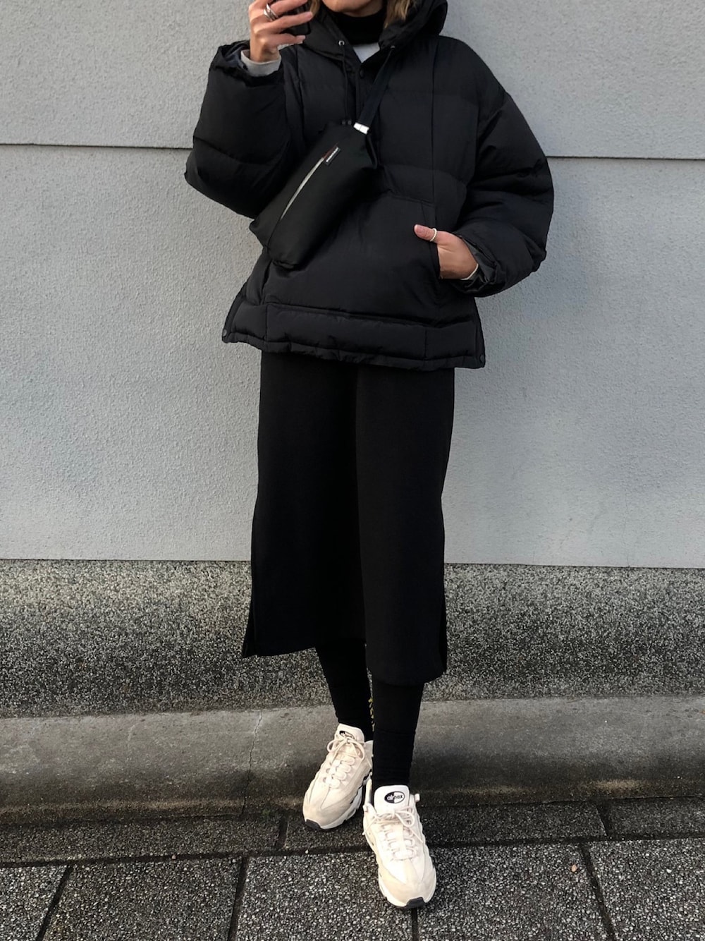 ブラック系のボディバッグ/ウエストポーチ、ベージュ系のスニーカー、ブラック系のダウンジャケット/コートを着用したレディースの冬コーディネートの1枚目の写真
