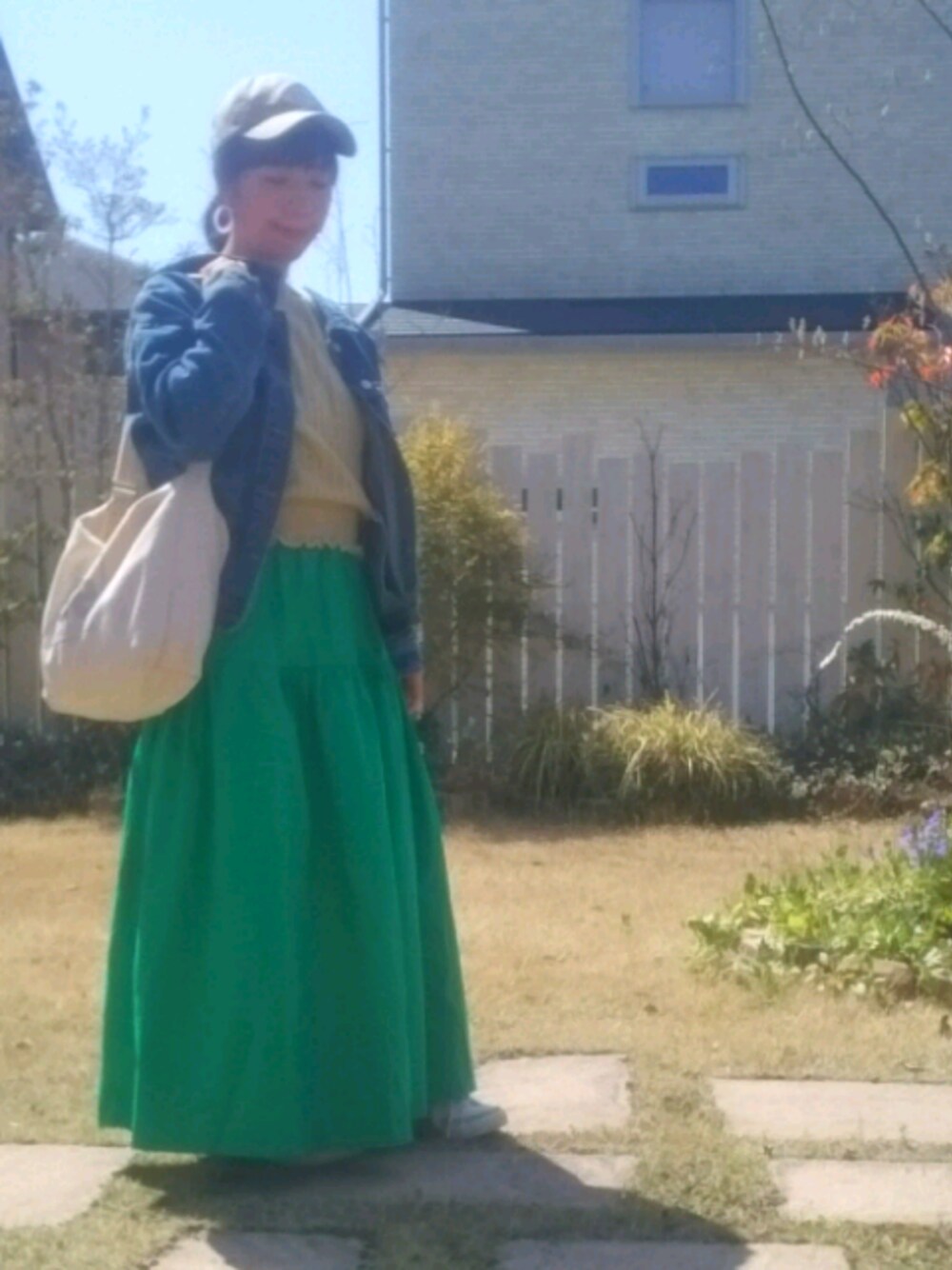 ブルー系のデニムジャケット、イエロー系のニット/セーター、グリーン系のスカートを着用したレディースの春コーディネートの1枚目の写真