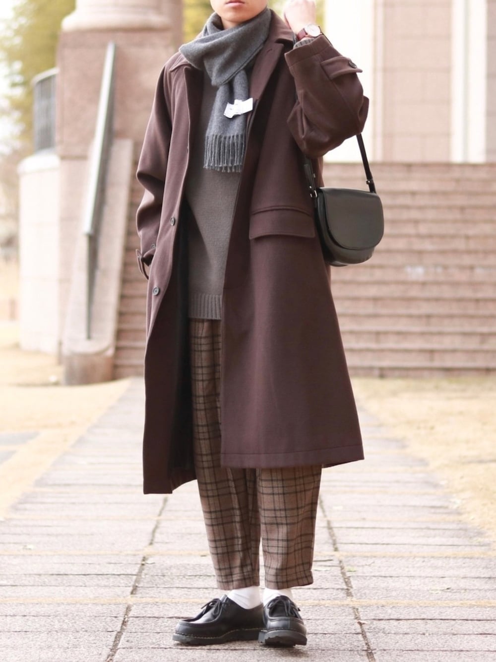 ブラウン系のステンカラーコート、グレー系のニット/セーター、ブラウン系のその他パンツを着用したメンズの冬コーディネートの1枚目の写真