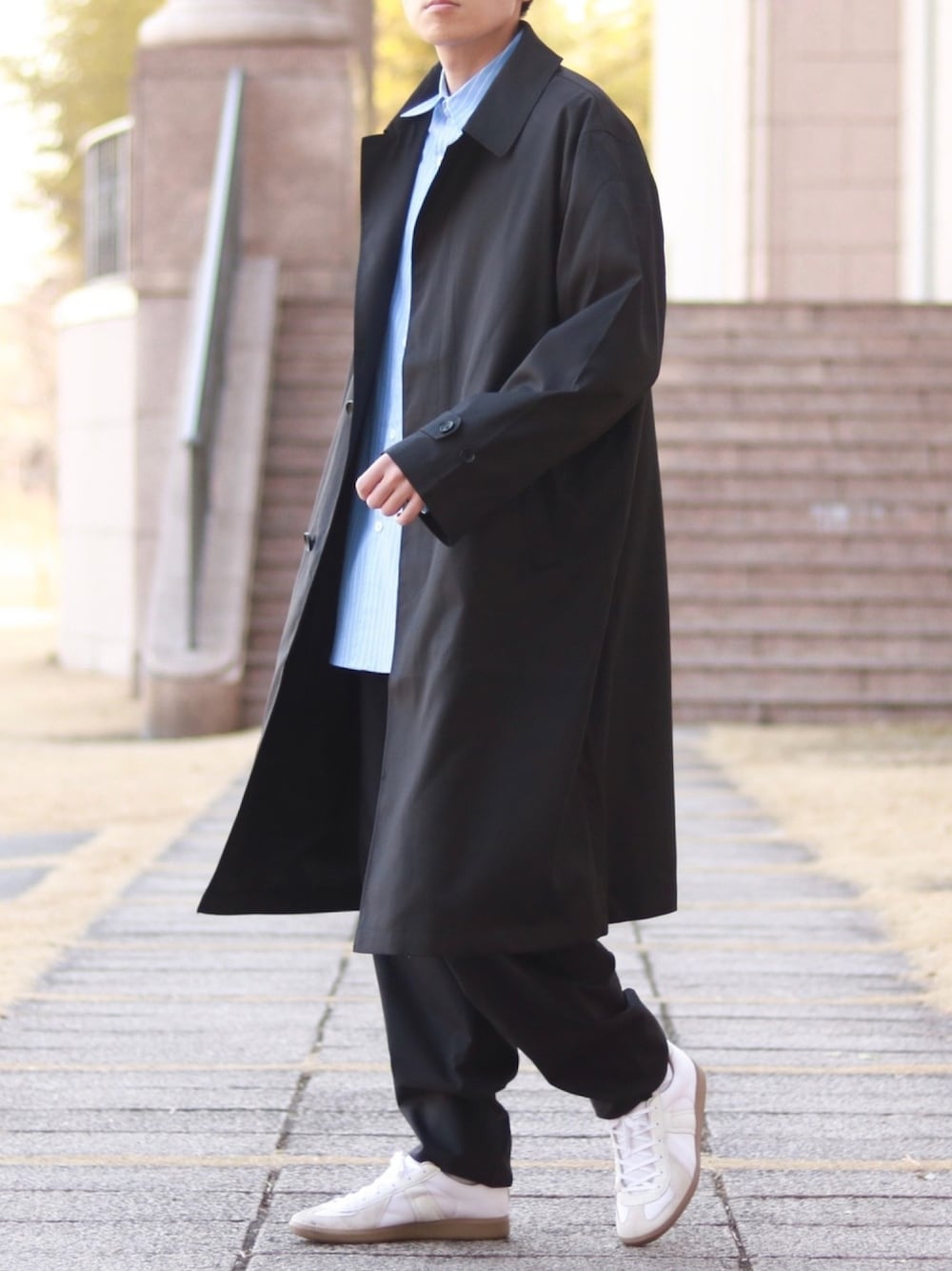 「大人カジュアル、春コーデ、春色、ステンカラーコート、モノトーン、ストライプ、ストライプシャツ、差し色、スニーカーコーデ、白スニーカー」｜「ADRERのオーバースプリングステンカラーコート（ステンカラーコート、ブラック系）」を使った、howellさん（メンズ・175cm）の冬コーディネートの1枚目の写真