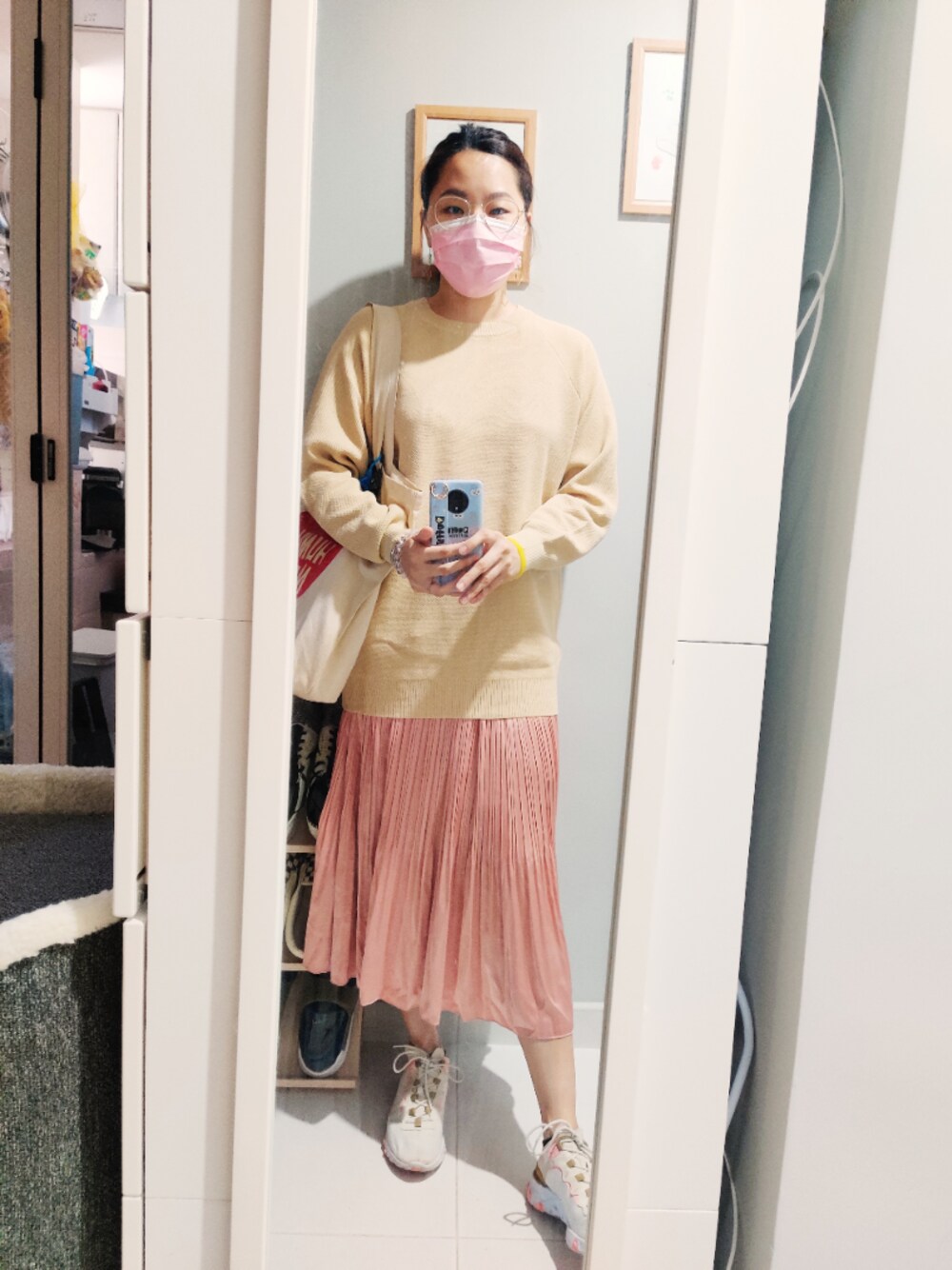 ピンク系のスカート、ベージュ系のカーディガン/ボレロ、ベージュ系のスニーカーを着用したレディースの秋コーディネートの1枚目の写真