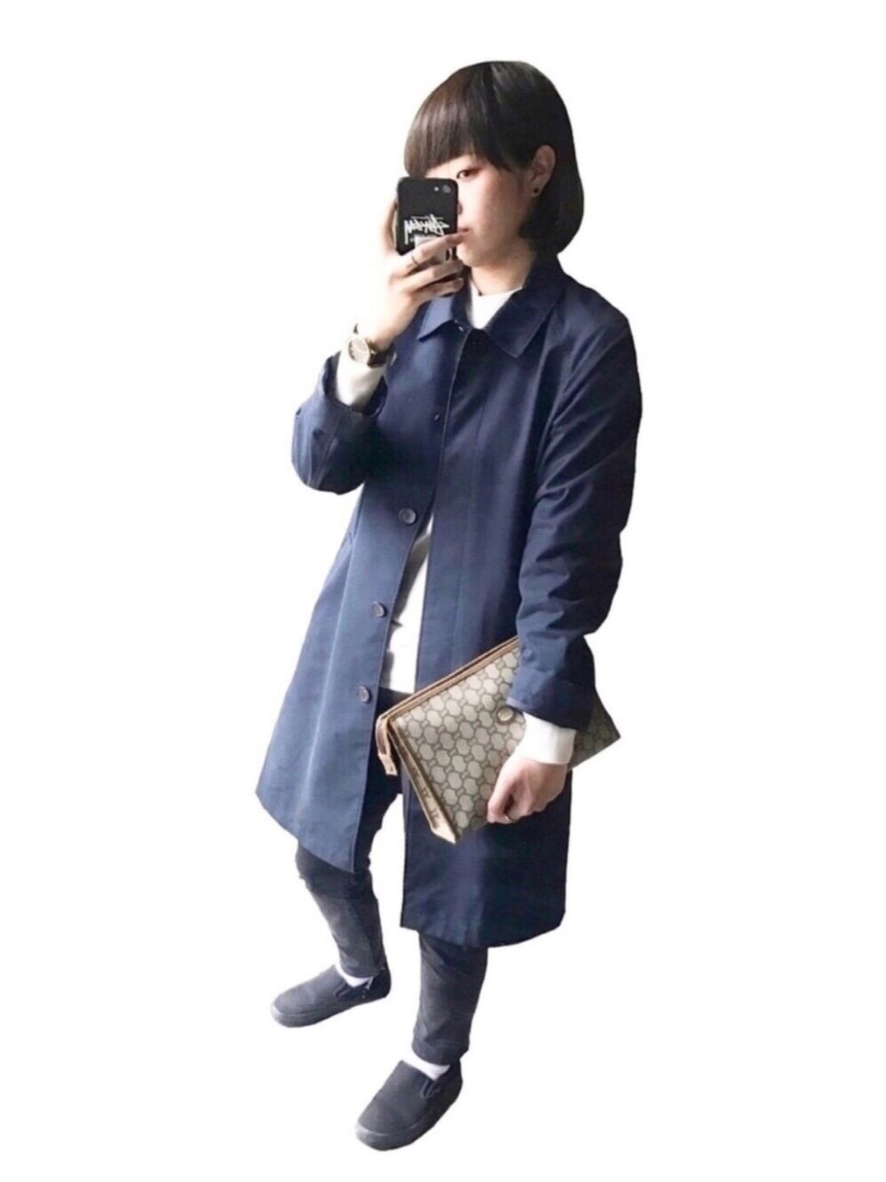 ブルー系のトレンチコート、ベージュ系のクラッチバッグ、ブラック系のデニムパンツを着用したレディースの春コーディネートの1枚目の写真