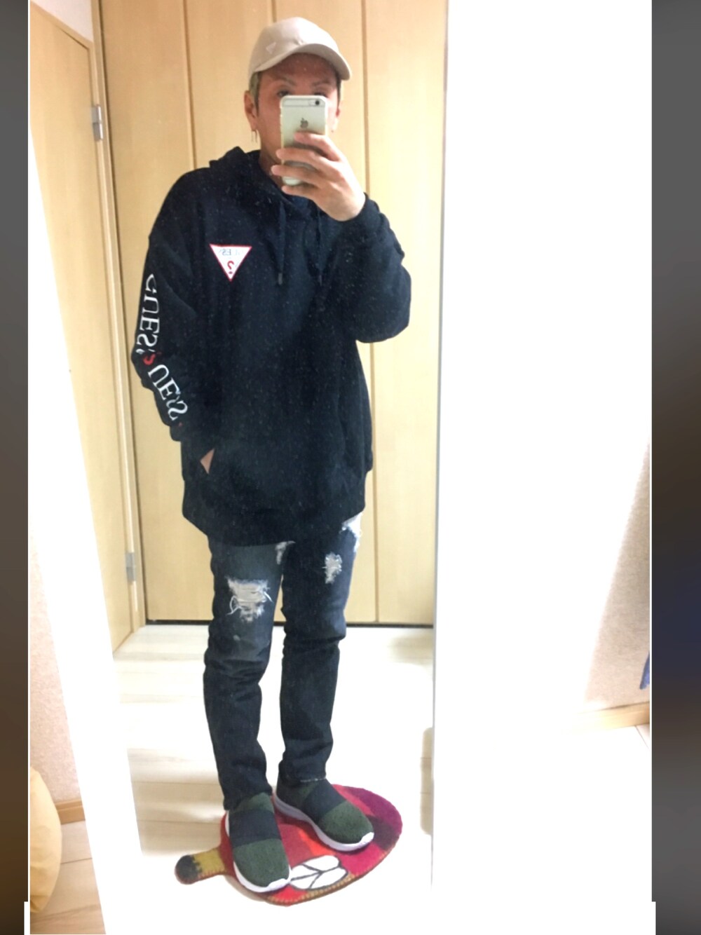 ブラック系のパーカー、ブラック系のデニムパンツ、グリーン系のスニーカーを着用したメンズの秋コーディネートの1枚目の写真