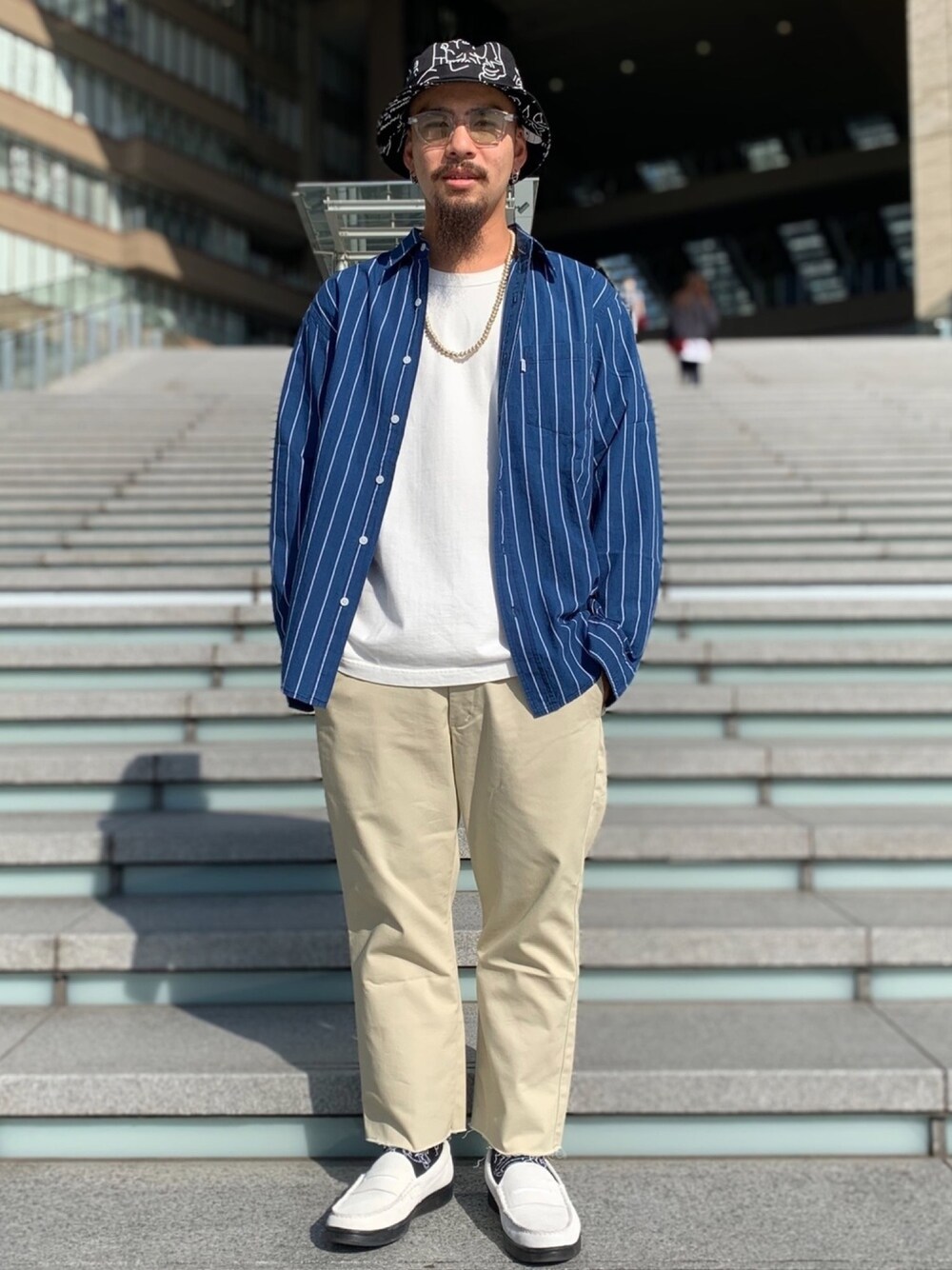 ホワイト系のスニーカー、ベージュ系のスラックス、ホワイト系のTシャツ/カットソーを着用したメンズの春コーディネートの1枚目の写真