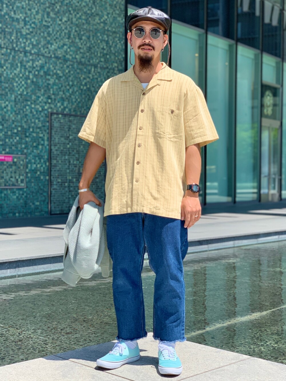 ブルー系のデニムパンツ、ブルー系のスニーカー、グリーン系のカーディガン/ボレロを着用したメンズの春コーディネートの1枚目の写真