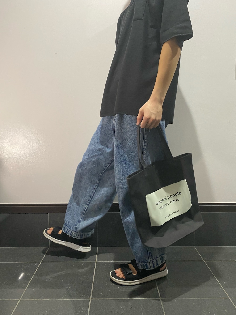 ブラック系のTシャツ/カットソー、ブラック系のトートバッグ、ブルー系のデニムパンツを着用したメンズの夏コーディネートの1枚目の写真