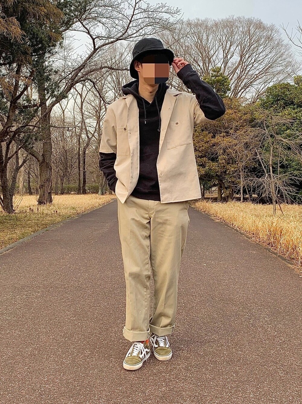 グリーン系のスニーカー、ベージュ系のチノパンツ、ブラック系のパーカーを着用したメンズの冬コーディネートの1枚目の写真