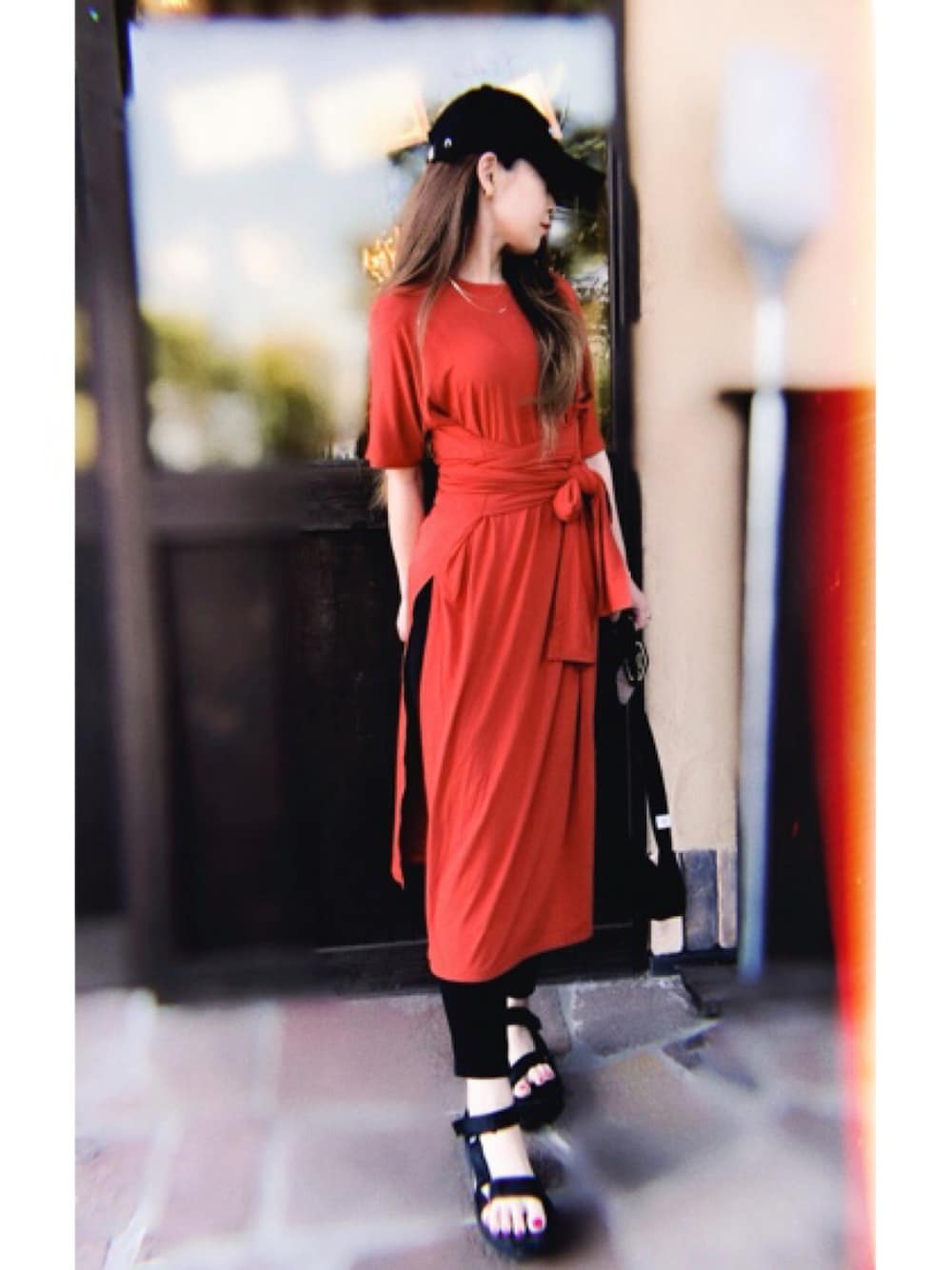 レッド系のワンピース、ブラック系のパンツ、ブラック系のサンダルを着用したレディースの夏コーディネートの1枚目の写真