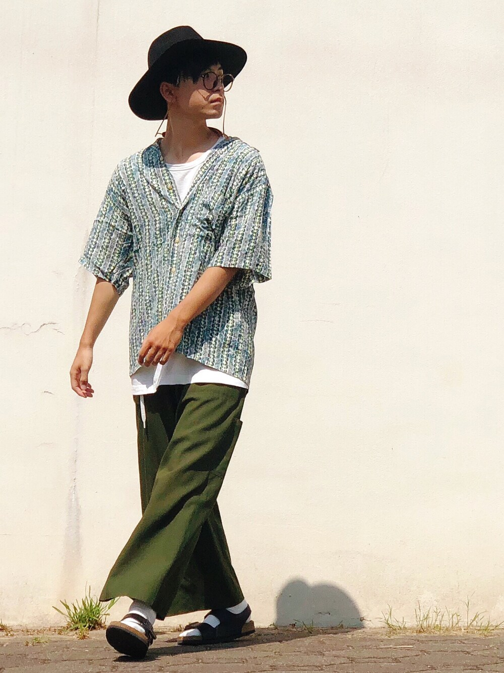 ブラック系のサンダル、ブラック系のハット、ブラウン系のメガネを着用したメンズの夏コーディネートの1枚目の写真