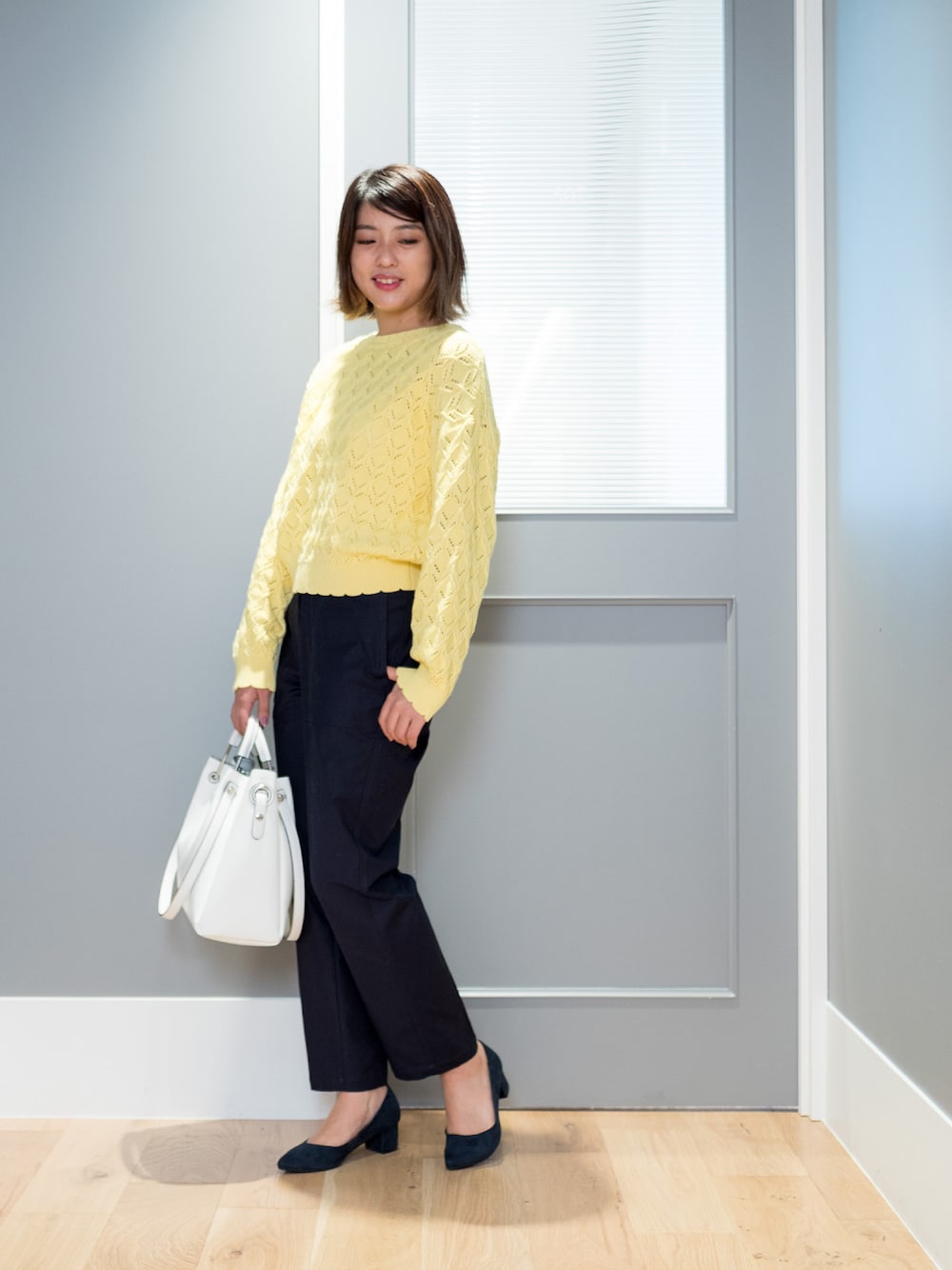 イエロー系のニット/セーター、ブルー系のその他パンツ、ホワイト系のショルダーバッグを着用したレディースの冬コーディネートの1枚目の写真