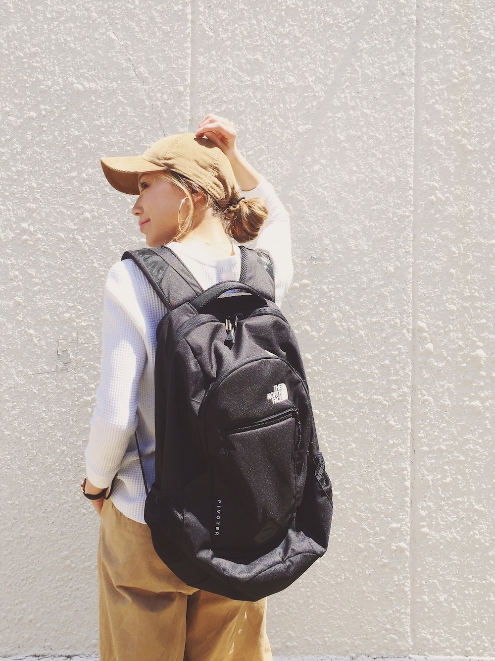 ホワイト系のTシャツ/カットソー、ブラック系のバックパック/リュック、ベージュ系のパンツを着用したレディースの春コーディネートの1枚目の写真