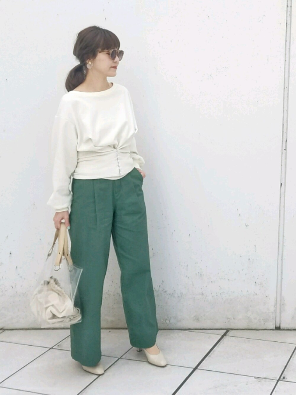 ホワイト系のトップス、グリーン系のチノパンツ、ベージュ系のバッグを着用したレディースの冬コーディネートの1枚目の写真