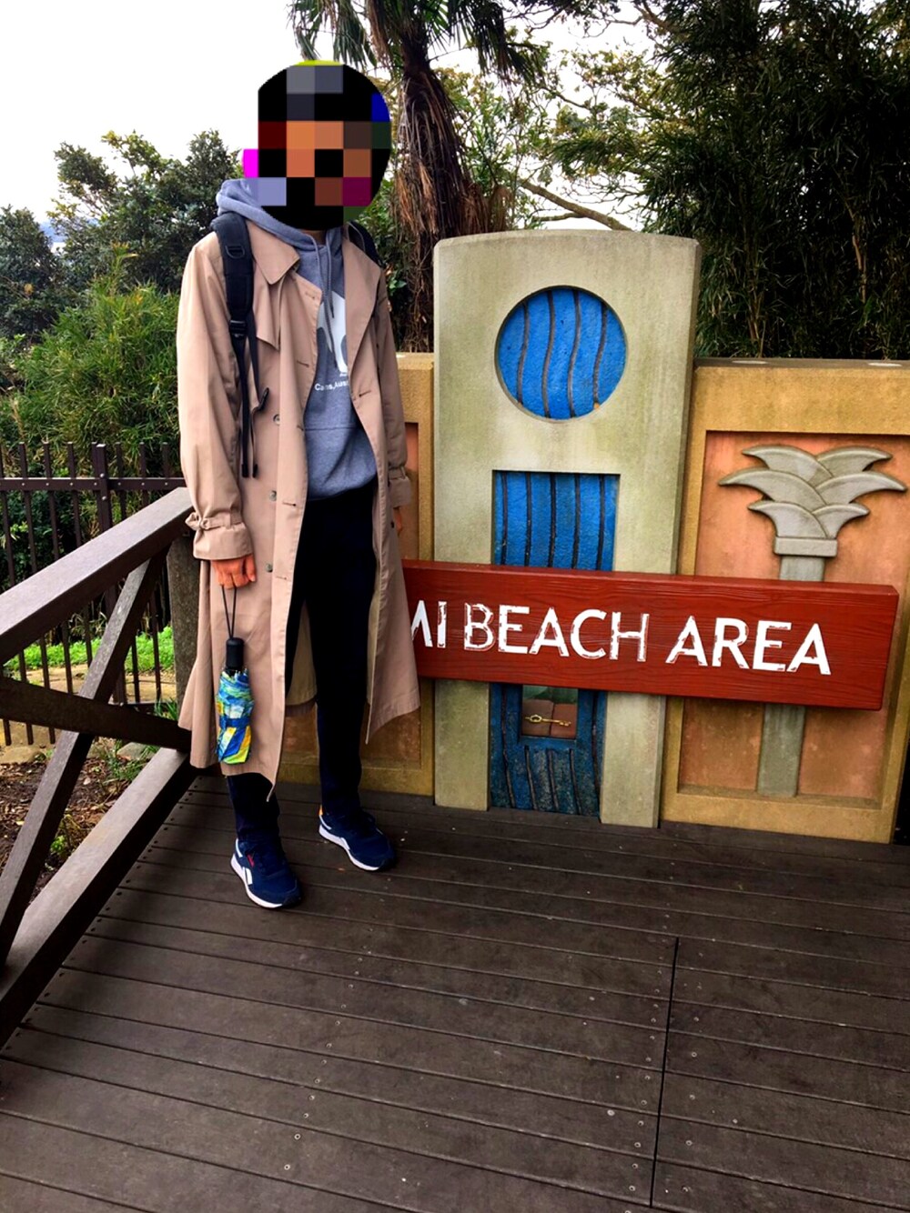 ベージュ系のトレンチコート、ブルー系のスニーカー、ブラック系のチノパンツを着用したメンズの冬コーディネートの1枚目の写真