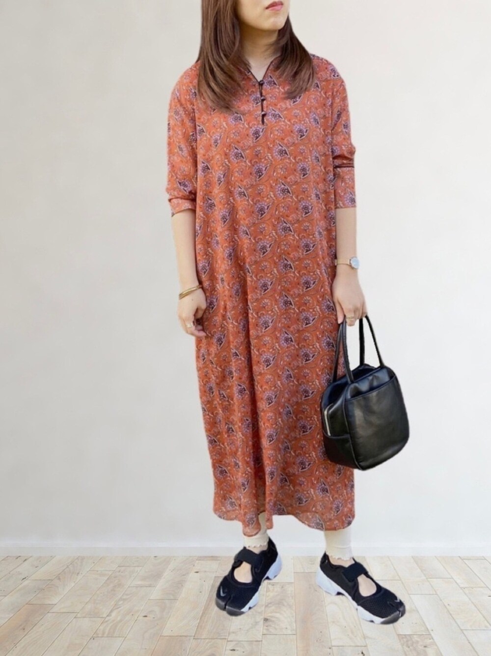 オレンジ系のワンピース、ブラック系のサンダル、ブラック系のボストンバッグを着用したレディースの春コーディネートの1枚目の写真