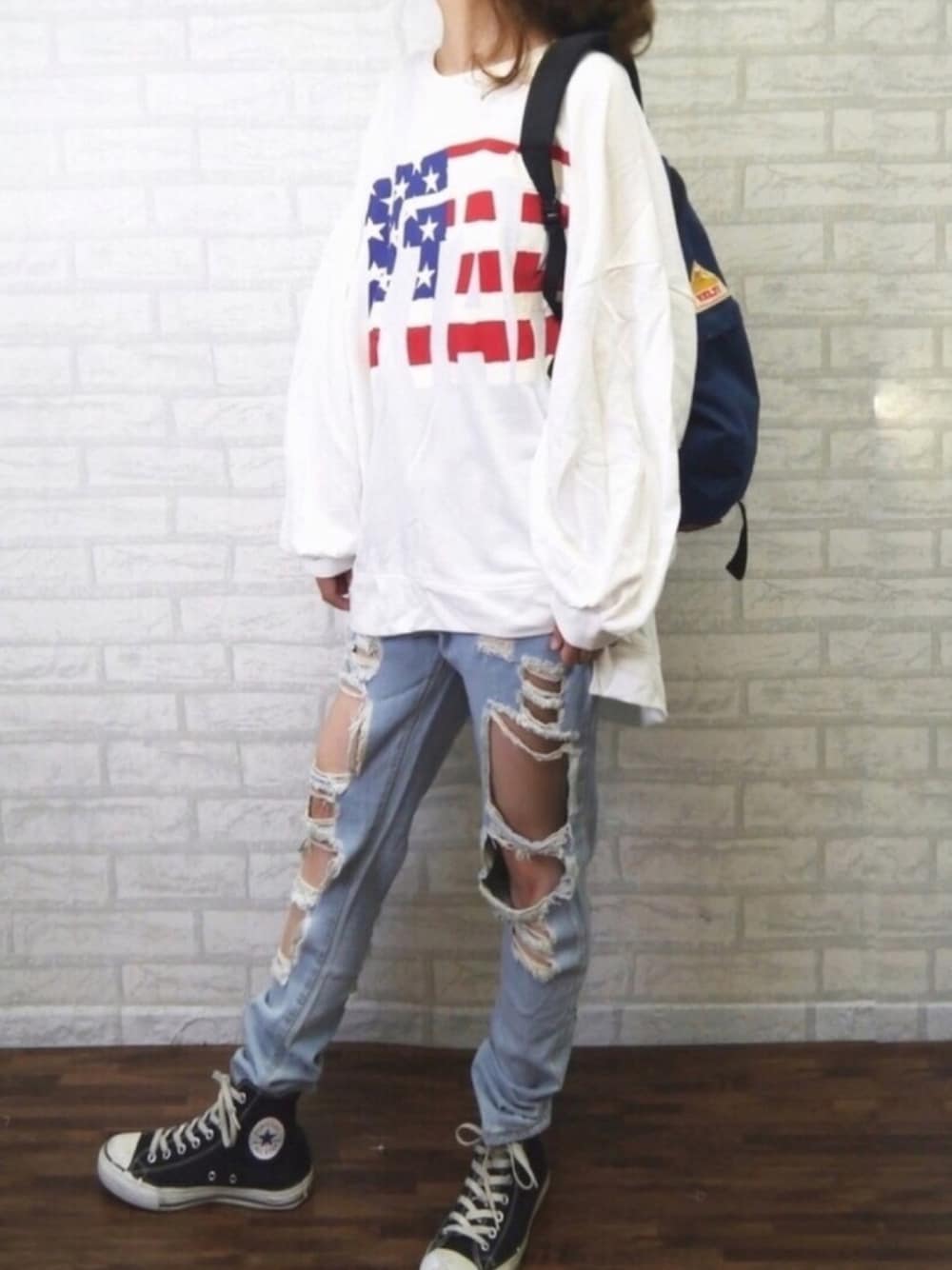 ブラック系のスニーカー、ブルー系のバックパック/リュック、ホワイト系のTシャツ/カットソーを着用したレディースの秋コーディネートの1枚目の写真