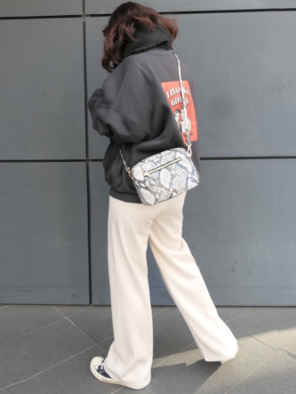 グレー系のショルダーバッグ、ブラック系のスウェット、ホワイト系のその他パンツを着用したレディースの冬コーディネートの1枚目の写真