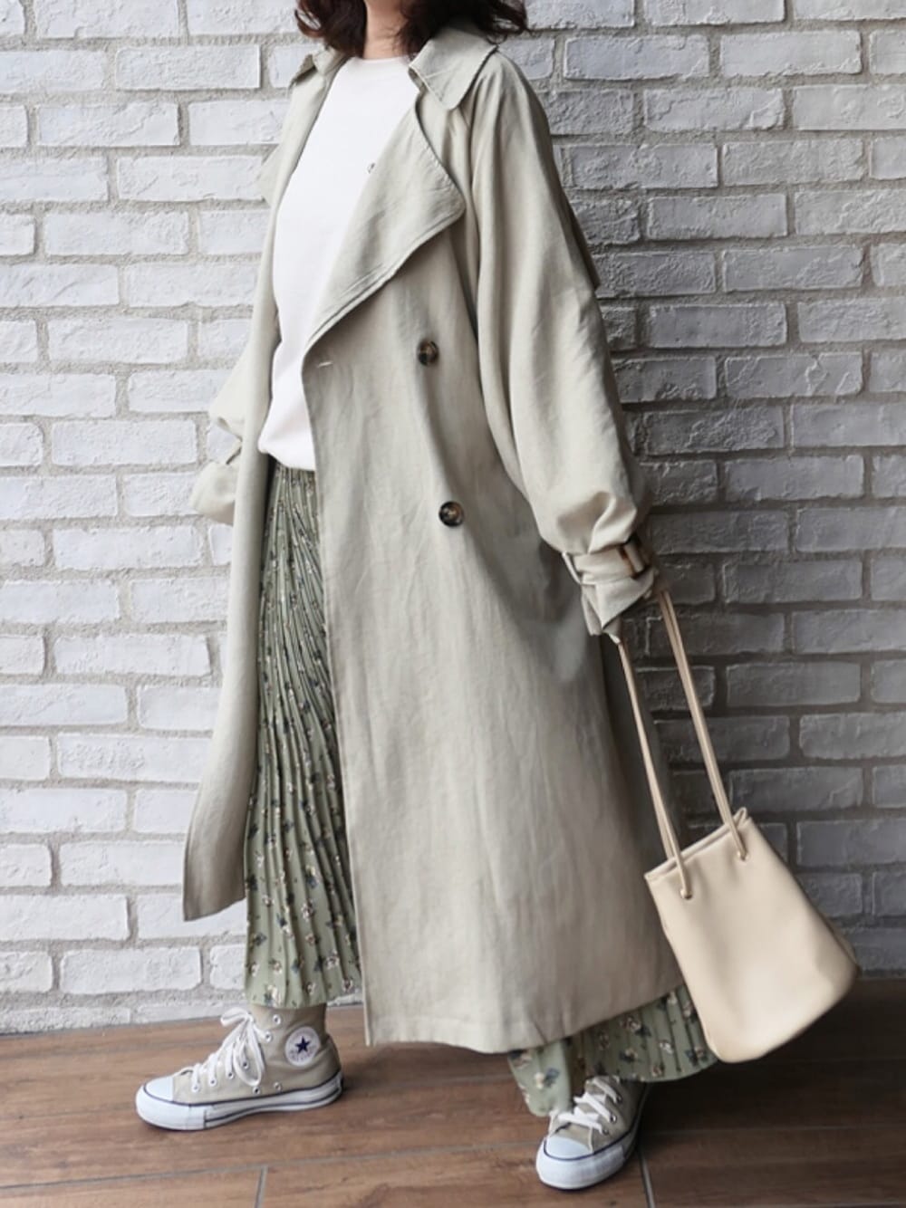 グリーン系のトレンチコート、グリーン系のスカート、ベージュ系のハンドバッグを着用したレディースの冬コーディネートの1枚目の写真