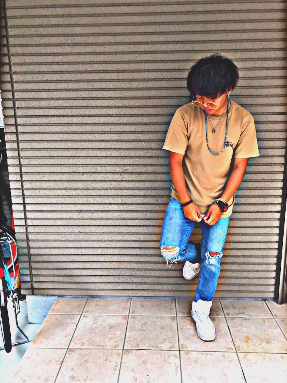 ベージュ系のTシャツ/カットソー、ブルー系のデニムパンツ、ホワイト系のスニーカーを着用したメンズの夏コーディネートの1枚目の写真