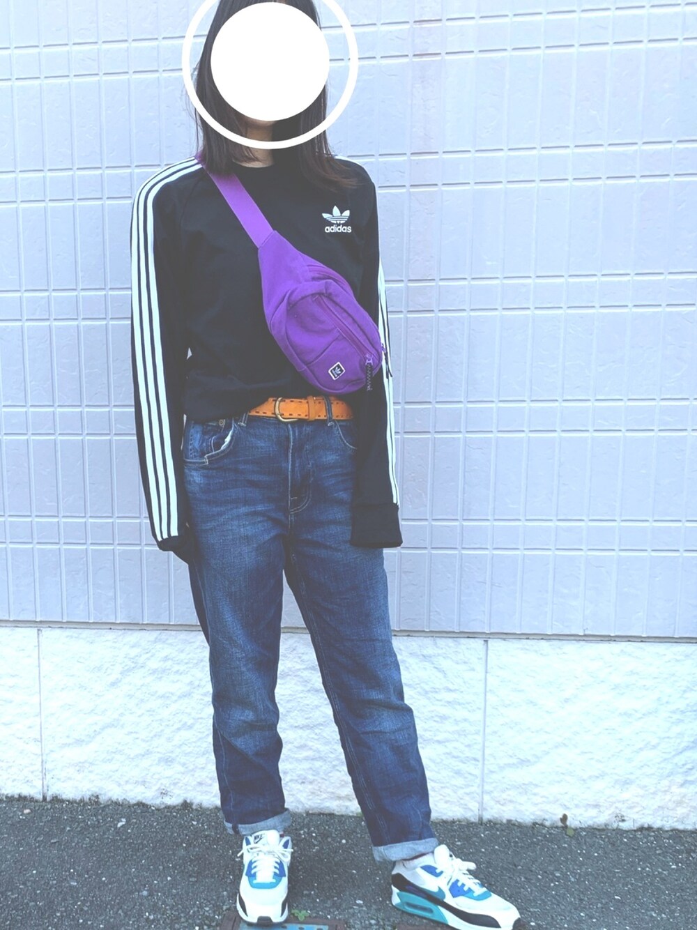 ブルー系のデニムパンツ、ブラック系のトップス、オレンジ系のベルトを着用したレディースの春コーディネートの1枚目の写真