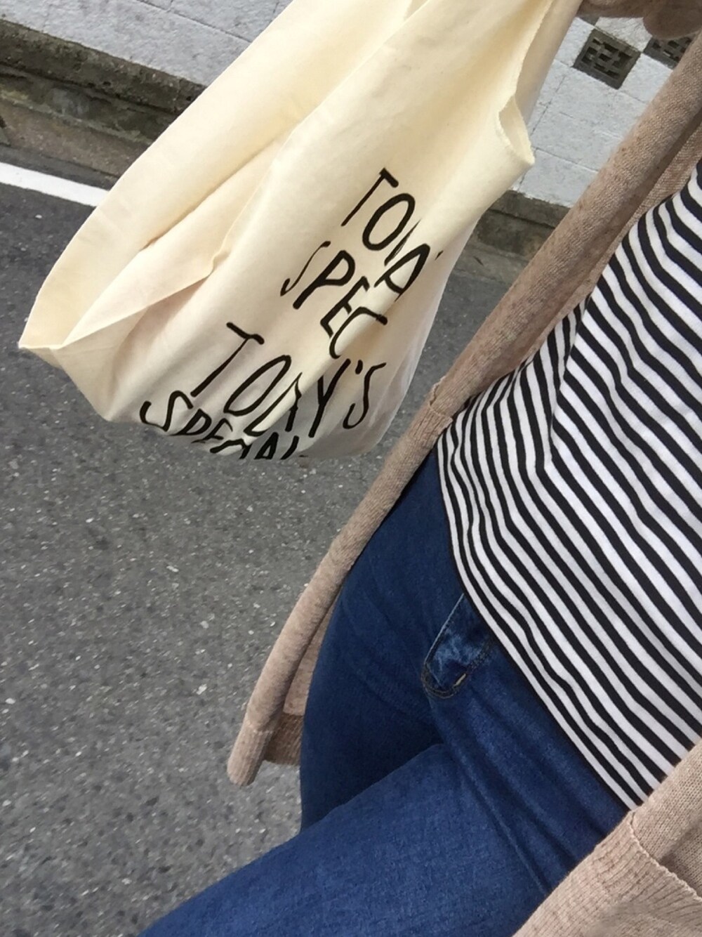 ホワイト系のエコバッグ/サブバッグ、ブラック系のTシャツ/カットソー、ブルー系のデニムパンツを着用したレディースの春コーディネートの1枚目の写真