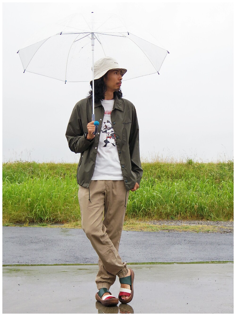 「チノパン、コーチジャケット、サンダル、コロンビア、Columbia、バケットハット、雨の日コーデ、白Tシャツ、キャラT、コラボTシャツ」｜「Columbiaのシッカモアバケット（ハット、ベージュ系）」を使った、つちぽんさん（メンズ・177cm）の夏コーディネートの1枚目の写真