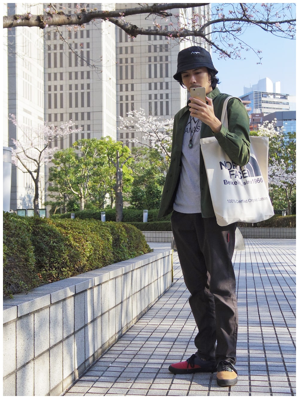 グリーン系のシャツ/ブラウス、グレー系のTシャツ/カットソー、ブルー系のトートバッグを着用したメンズの春コーディネートの1枚目の写真