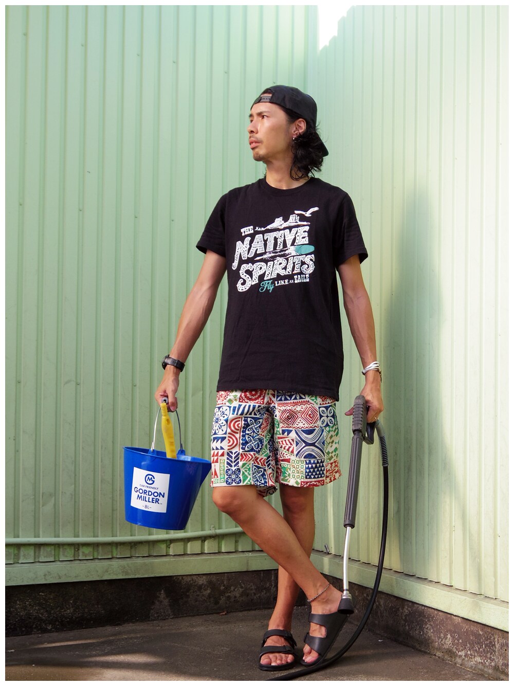「ショートパンツ、ハーフパンツ、ベースボールキャップ、サンダル、柄×柄、Columbia、チャイハネ、黒Tシャツ、バケツ」｜「チャイハネの【チャイハネ】THE NAVIVE SPIRITS CAY-Tシャツ Lサイズ（Tシャツ/カットソー、ブラック系）」を使った、つちぽんさん（メンズ・177cm）の夏コーディネートの1枚目の写真