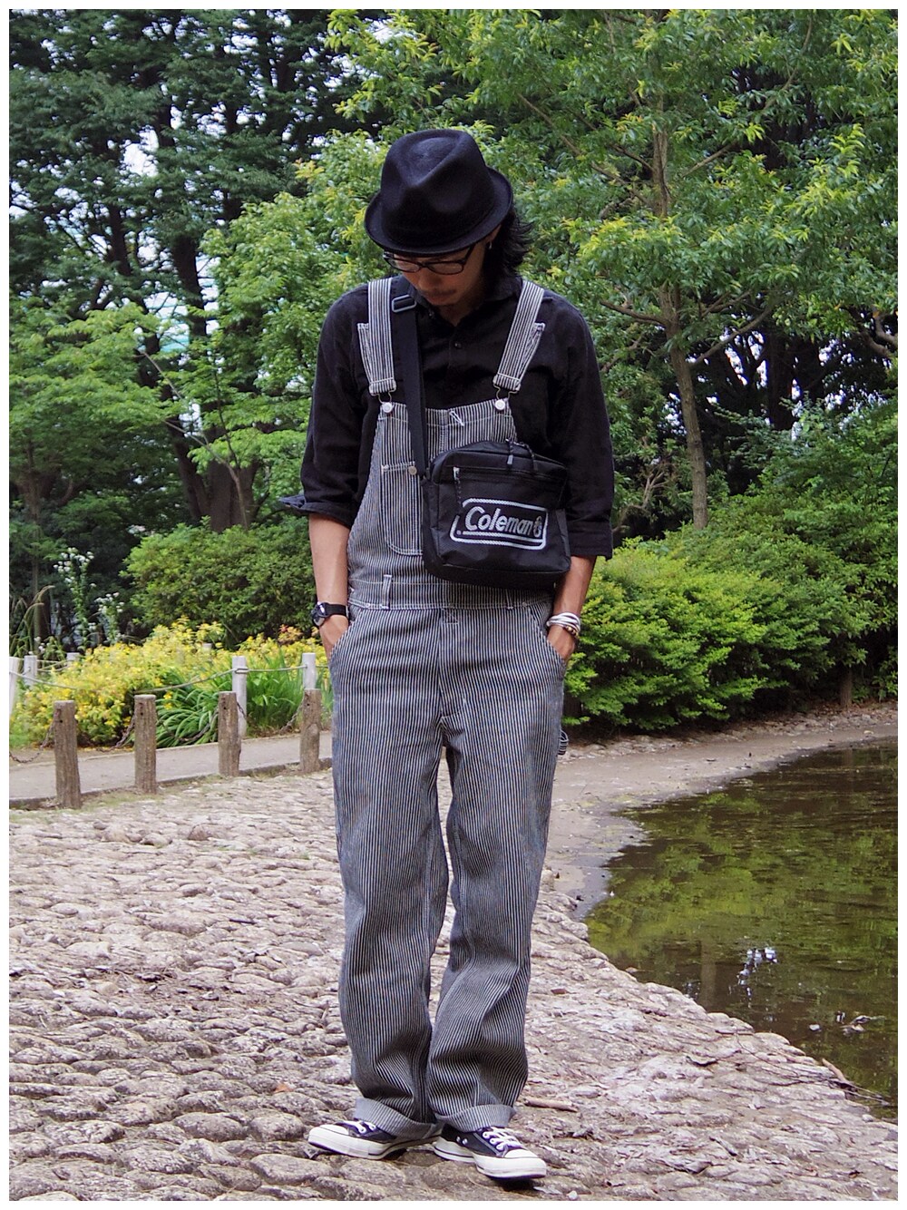 ブラック系のサロペット/オーバーオール、ブラック系のシャツ/ブラウス、ブラック系のショルダーバッグを着用したメンズの夏コーディネートの1枚目の写真