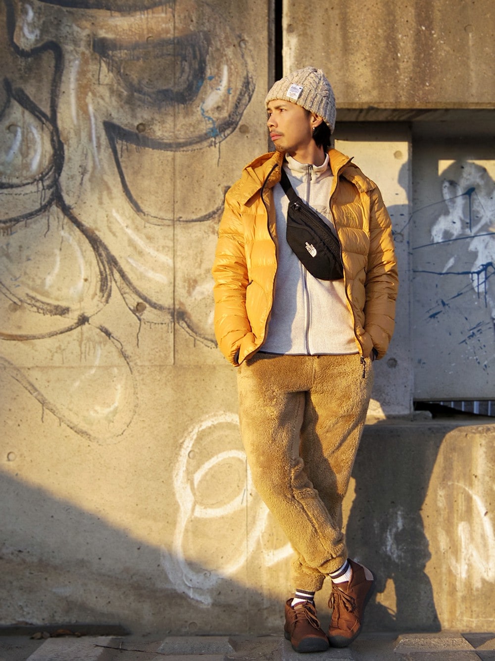 イエロー系のダウンジャケット/コート、ホワイト系のその他アウター、ブラック系のボディバッグ/ウエストポーチを着用したメンズの冬コーディネートの1枚目の写真