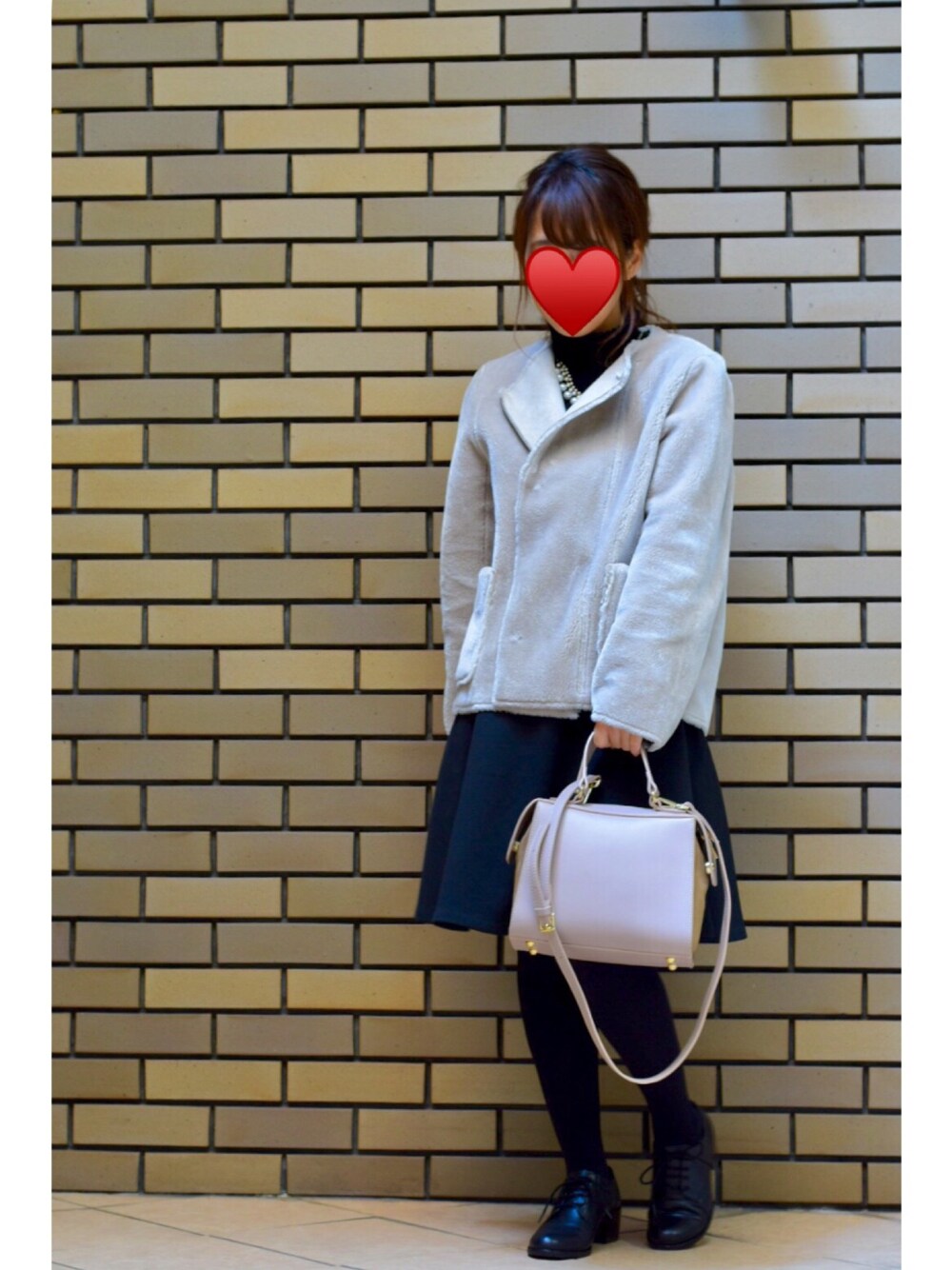 グレー系のムートンコート、ブラック系のニット/セーター、ブラック系のスカートを着用したレディースの冬コーディネートの1枚目の写真