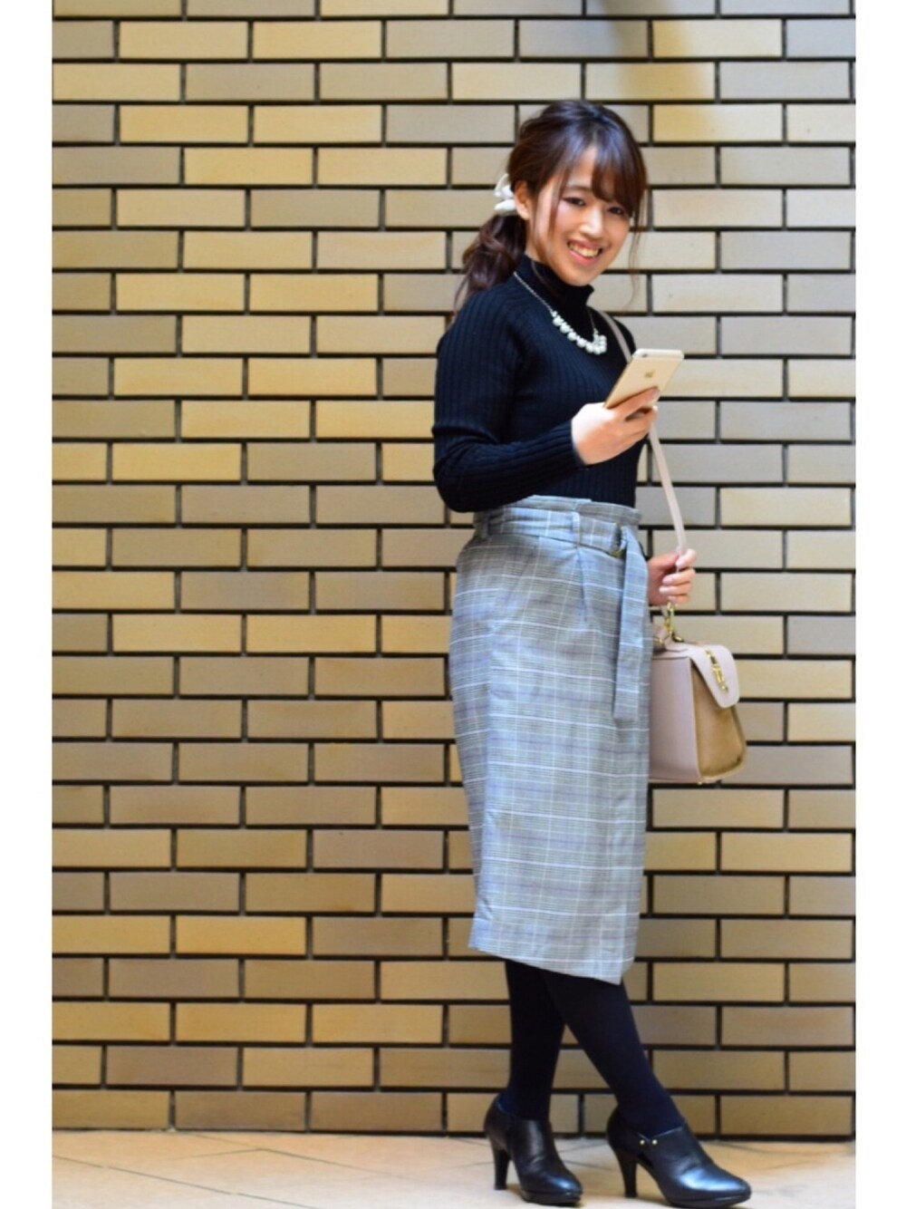 ブラック系のニット/セーター、ベージュ系のショルダーバッグ、ブラック系のブーティを着用したレディースの冬コーディネートの1枚目の写真