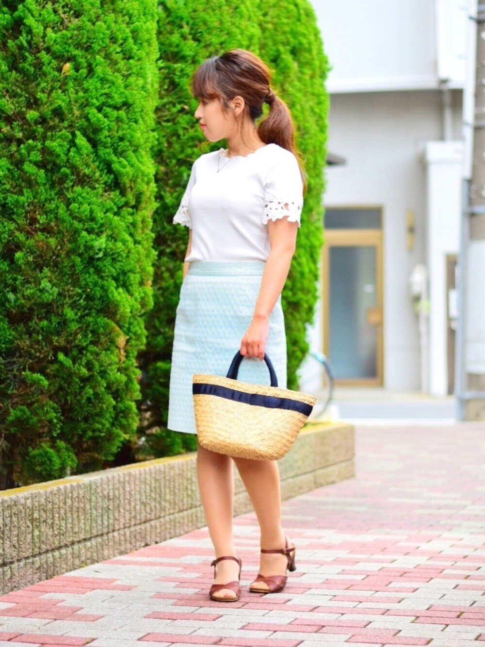 ブラウン系のサンダル、ベージュ系のかごバッグ、グリーン系のスカートを着用したレディースの夏コーディネートの1枚目の写真