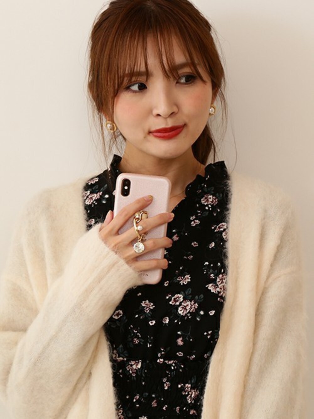 ベージュ系のカーディガン/ボレロ、ブラック系のワンピース、ピンク系のスマホケース/カバーを着用したレディースの秋コーディネートの1枚目の写真