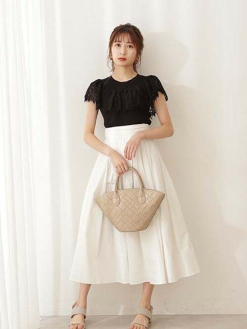 ホワイト系のスカート、ブラック系のニット/セーターを着用したレディースの夏コーディネートの1枚目の写真